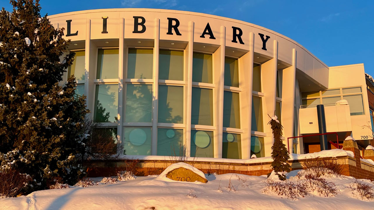 The front windows of the library glow gold in a winter sunset.