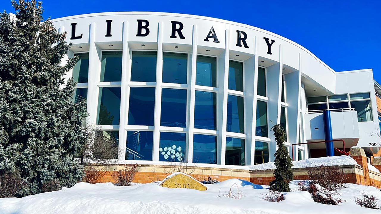 The front windows of the library on a sunny, snowy winter day.